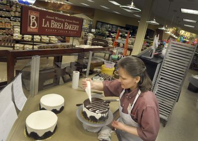 Anna Bezzabara works on a tuxedo cake in the refurbished bakery of the Five Mile Rosauers on Friday.  “We are all so happy be back home,” said store manager Terri Norton  of the 120 employees.  (Christopher Anderson / The Spokesman-Review)