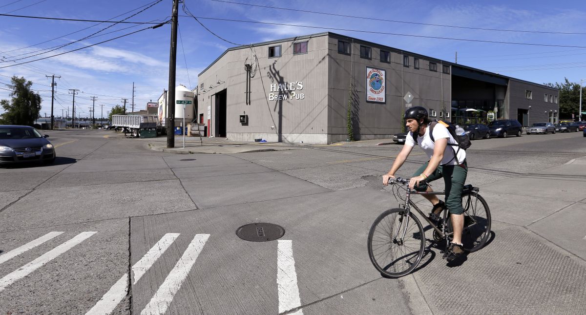 A bicyclist rides past Hale’s Ales brewery and pub in the Ballard neighborhood of Seattle last week. In the neighborhood, home to fishing shops, shipyards and boat fueling facilities for decades, six breweries have sprung up in the past two years, joining Hale’s and Maritime Pacific Brewing, which both opened in the 1990s. (Associated Press)