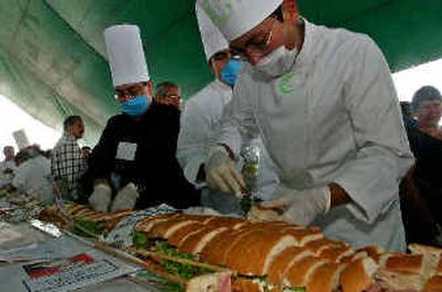 
Chefs take a piece of a 25-yard-long mega-torta during the the celebration of Mexico's first national Torta Festival in Mexico City on Friday.
 (Associated Press / The Spokesman-Review)
