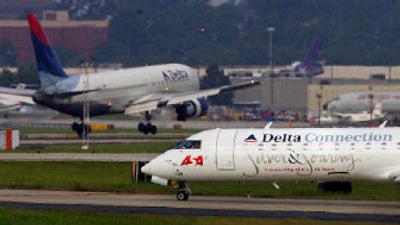
A commuter jet taxis to the runway as a Delta jet arrives at Atlanta Hartsfield Jackson International Airport.  
 (Associated Press / The Spokesman-Review)