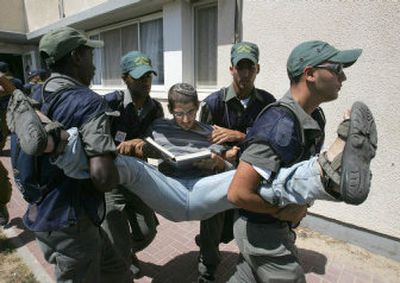 
Israeli border policemen carry a Jewish settler holding a book out of the synagogue in the Jewish settlement of Elei Sinai in the northern Gaza Strip during its forced evacuation on Sunday.
 (Associated Press / The Spokesman-Review)