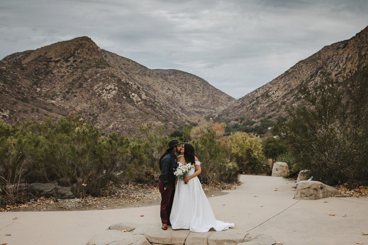 In this Sunday, Dec. 27, 2020 photo provided by Kristen Pritchard Photography, Kayleigh and Cody Cousins pose for wedding photos at Mission Trails Regional Park in San Diego, Calif. They initially planned an April 2020 wedding, postponed it after the pandemic took hold, rescheduled it for December, then had to shift gears again when a new lockdown was imposed. “That was devastating,” said Kayleigh. “We said, ‘Let’s just do it on Zoom.’”  (Kristen Pritchard)