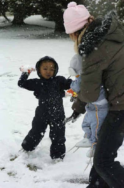 Darian Seuen, 3, throws a snowball at his aunt Khamphin Nanthavongdouangsk and her son, Shailon Ben, 5 months, in Lynden, Wash., Thursday. The families just moved from California and It was Darian's first time playing in the snow.
(Associated Press / The Spokesman-Review)
