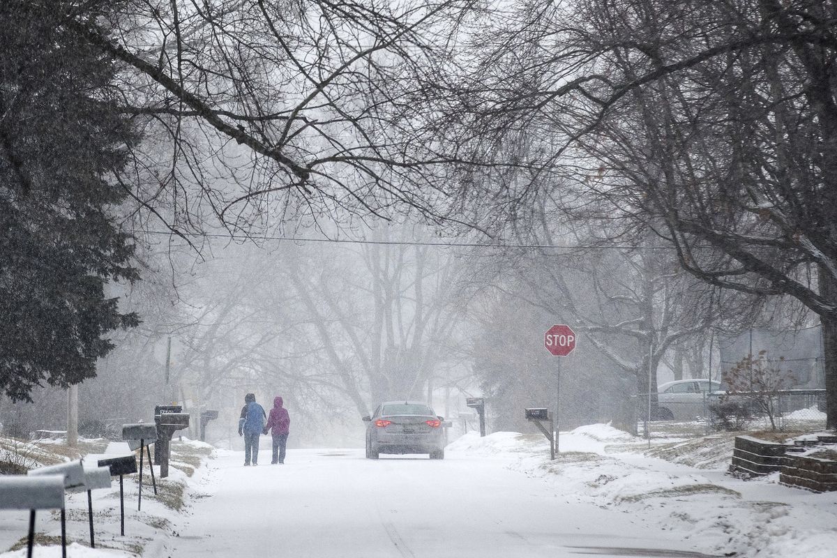 Two people hold hands while walking south on Madison Street toward 27th Avenue in Bellevue, Neb., during a winter storm warning on Monday, Jan. 25, 2021.  (Chris Machian)