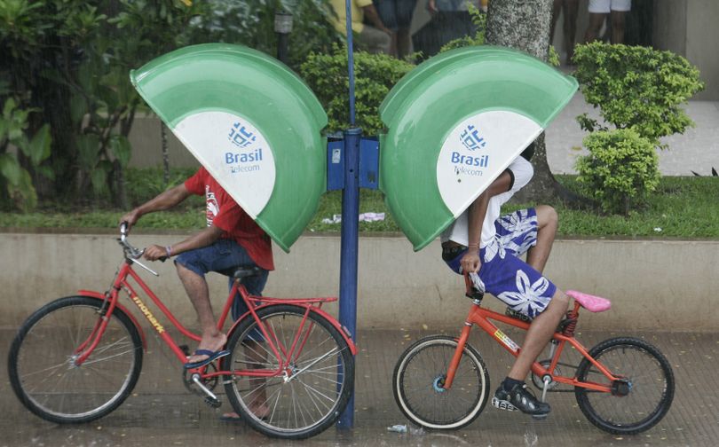 ORG XMIT: KNP109 Cyclists take cover from the rain in public phone booths in Rio Branco, Brazil, Tuesday, April 28, 2009. (AP Photo/Karel Navarro) (Karel Navarro / The Spokesman-Review)