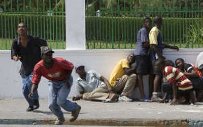 Demonstrators take cover from shooting in front of Haiti's presidential palace Tuesday in Port-au-Prince.Associated Press
(Associated Press / The Spokesman-Review)