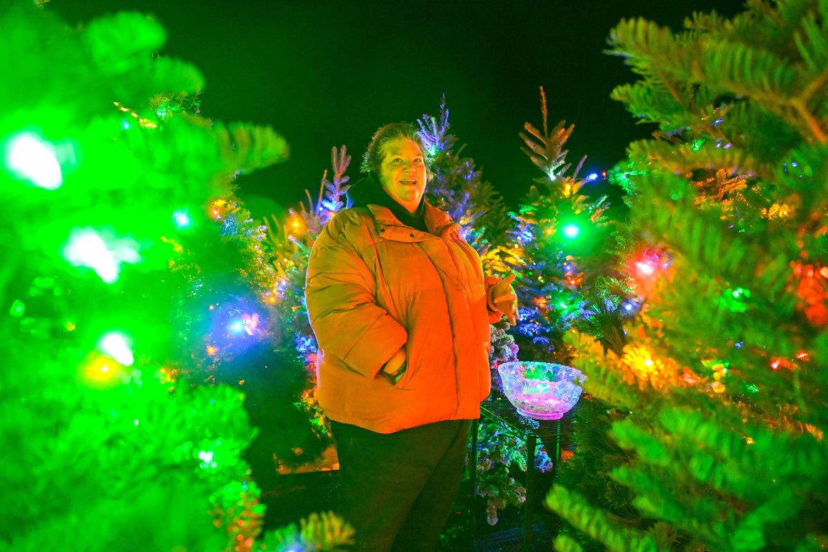 Paula Randall stands in the center of the Christmas Tree Labyrinth on Monday and talks about how she helped set up the display of holiday trees in the parking lot of the Chewelah Center for the Arts in Chewelah, Wash. Randall is a volunteer at the center. Next to her is a bowl filled with crystals that visitors are encouraged to take home after they’ve taken a contemplative walk through the display.  (Jesse Tinsley/THE SPOKESMAN-REVI)