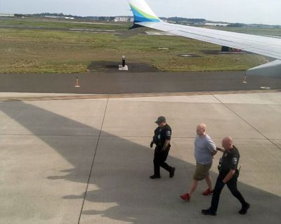 Alaska Airlines passenger Brandon L. Scott is led away by authorities after his arrest Wednesday at Spokane International Airport. (Courtesy Scott Mackie)