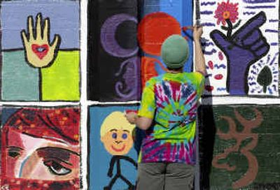 
Emily Himelright, 18, adds orange paint to her artwork at the People's Gallery on the  south side of the railroad viaduct between Post and Howard streets. 
 (SR / The Spokesman-Review)