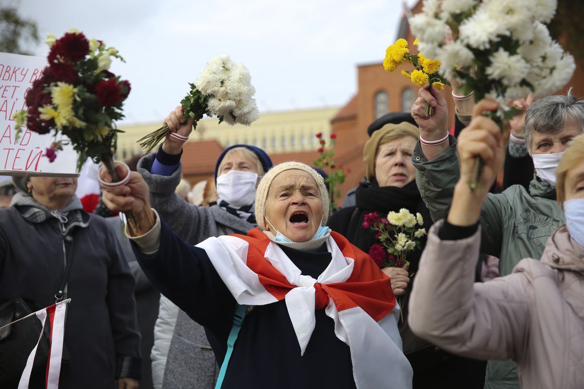 People, most of them pensioners, wave bunches of flowers during an opposition rally to protest the official presidential election results in Minsk, Belarus, Monday, Oct. 26, 2020. Factory workers, students and business owners in Belarus have started a general strike, calling for authoritarian President Alexander Lukashenko to resign after more than two months of mass protests triggered by a disputed election. (STR)