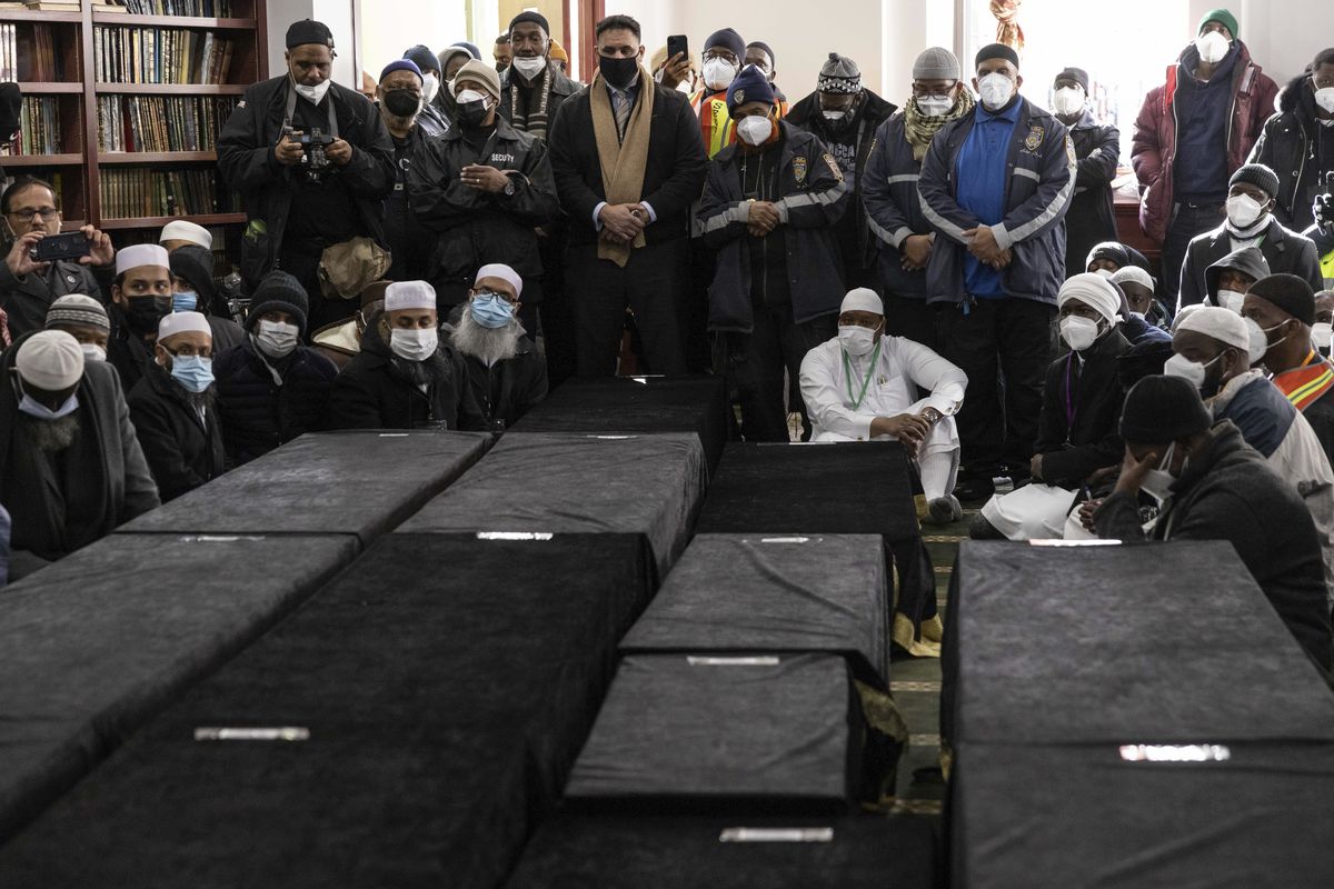 Caskets sit on the floor during the funeral service for victims from the apartment building which suffered the city