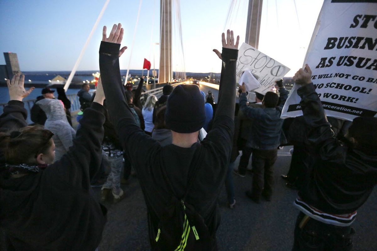 Protesters hold up their hands and signs on the cable bridge Saturday, Feb. 21, 2015, during a protest stemming from the officer involved shooting death of Antonio Zambrano-Montes. (Andrew Jansen / AP Photo/The Tri-City Herald)