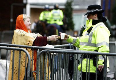 
A police officer hands a cup of tea to a lone protester Saturday outside Blackburn Cathedral before a visit by U.S. Secretary of State Condoleezza Rice and British Foreign Secretary Jack Straw. 
 (Associated Press / The Spokesman-Review)