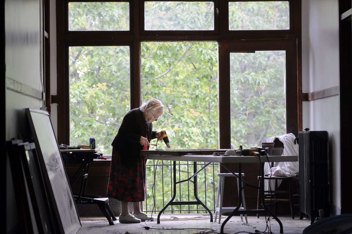 Alvina Urban, 90, uses a heat gun and putty knife to scrape old paint from window frames at the Mount St. Michael complex. (Dan Pelle)