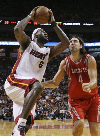 Miami’s LeBron James, driving against Houston’s Luis Scola, scored 33 points with 10 rebounds and seven assists. (Associated Press)