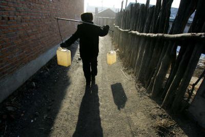 
A resident carries water containers to his home after filling them from a water truck in Dalianhe, China, Friday. The town has shut down its water supply because of a toxic slick in the nearby Songhua River. 
 (Associated Press / The Spokesman-Review)