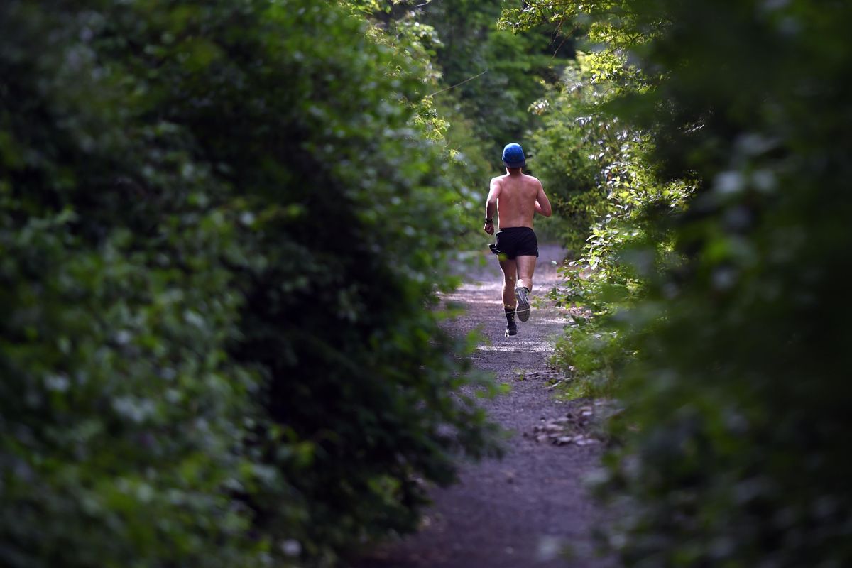 A jogger runs down the Ben Burr Trail, a mostly-unpaved hillside trail in the West Central neighborhood, which will soon be paved. (Jesse Tinsley / The Spokesman-Review)