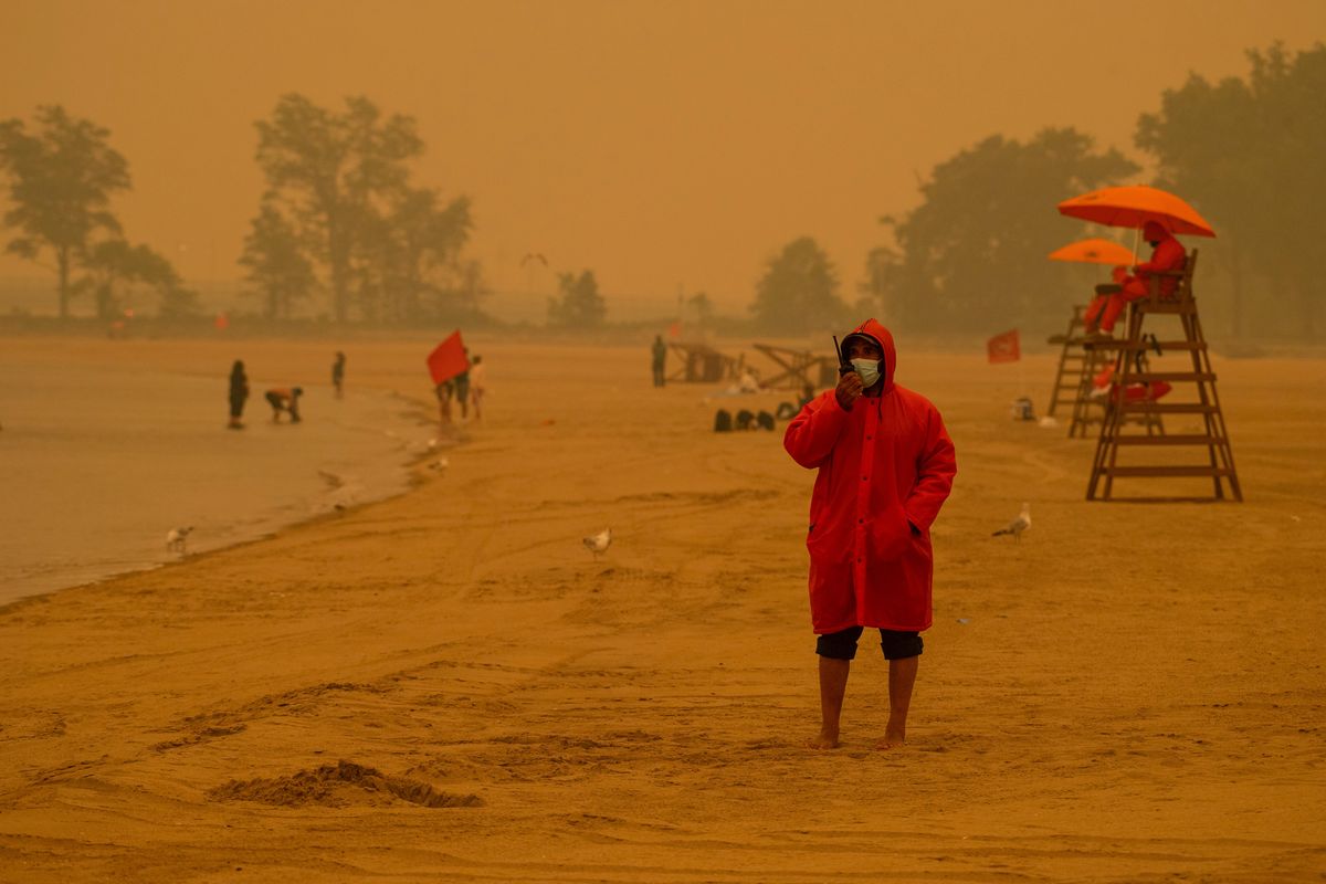 Lifeguards watch over a nearly empty Orchard Beach in the Bronx amid smoke from wildfires in Canada on Wednesday. Canada’s devastating fires and toxic smoke might not recur every year, but the heat from climate change increases the risks of a wide range of disasters. (GREGG VIGLIOTTI/New York Times)