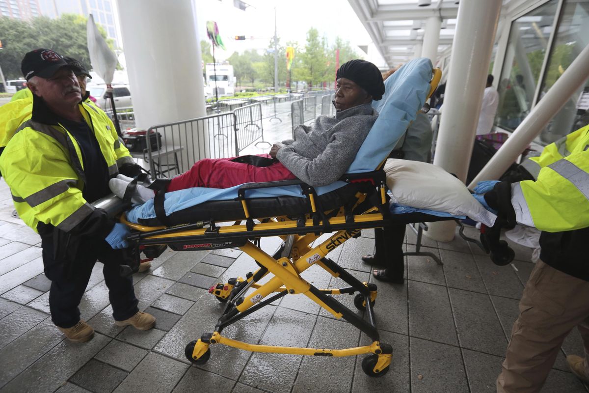 A woman is wheeled by first responders into the George R. Brown Convention Center that has been set up as a shelter for evacuees escaping the floodwaters from Tropical Storm Harvey in Houston, Texas, Tuesday, Aug. 29, 2017. (LM Otero / Associated Press)