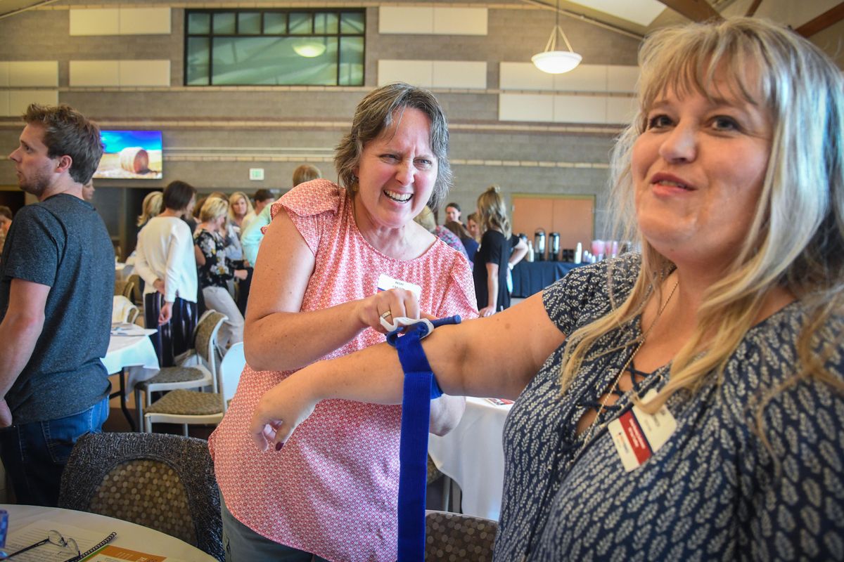 Deer Park School District nurse Becky Carlson, center, tightens  a tourniquet on the arm of Lisa Weinrich, also a Deer Park school nurse, Monday at CenterPlace in Spokane Valley. The pair were participating in the Stop the Bleed course during a conference for school nurses. (Dan Pelle / The Spokesman-Review)