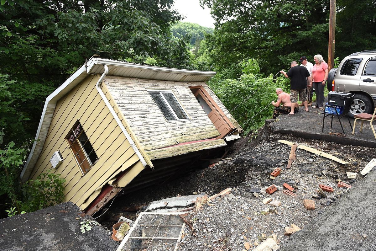 Employees and volunteers with Main Street Motors attempt to get company documents out of the building Friday June 24, 2016, in Richwood, W.Va., after the company’s building was knocked off its foundation by extensive flooding and hanging off the side of a hill. (Rick Barbero / The Register-Herald via Associated Press)