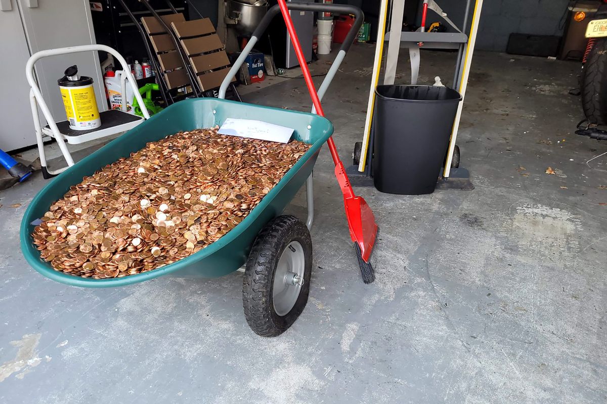 This image provided by Olivia Oxley shows a wheelbarrow filled with pennies, March 20, 2021 in Fayetteville, Ga. A Georgia man said his former employer owed him a pretty penny, $915 to be exact, after leaving his job in November. But Andreas Flaten said he was shocked to see his final payment: 90,000 oil or grease covered pennies, at the end of his driveway earlier this month, news outlets reported. Atop the pile was an envelope with Flaten