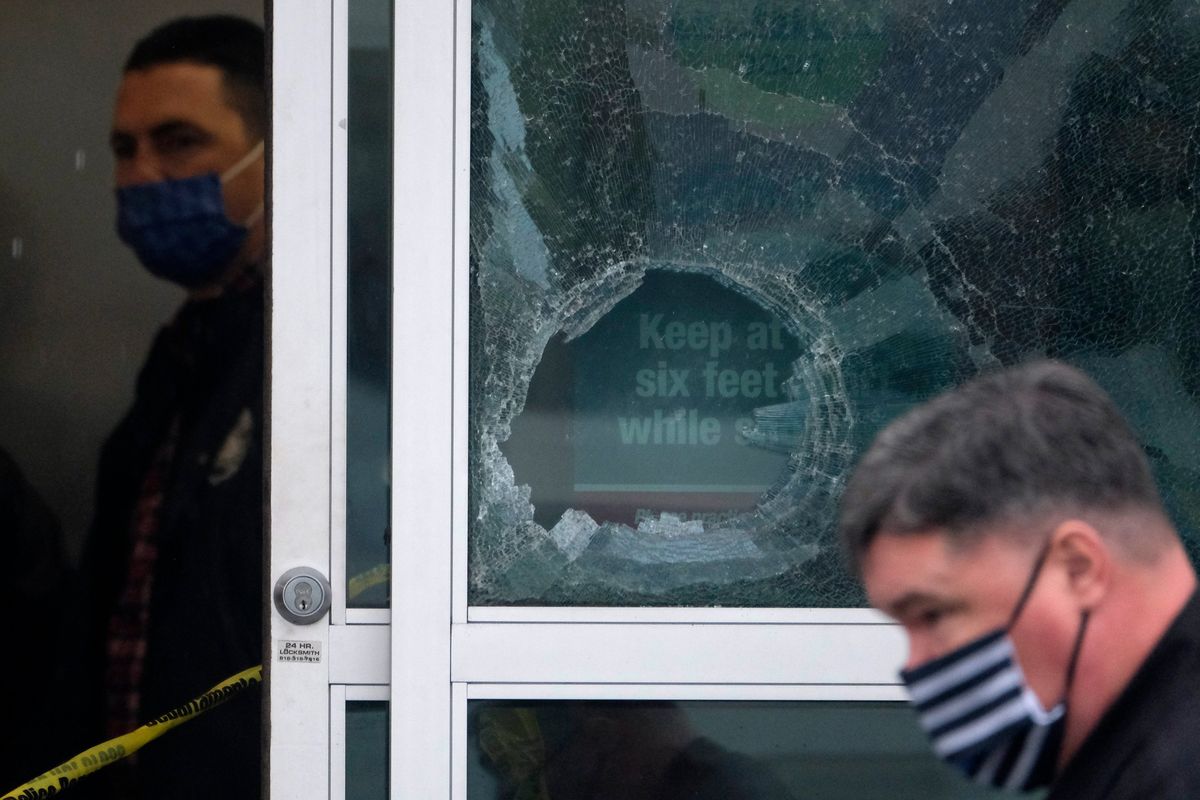 Police officers work near a broken glass door at the scene where two people were struck by gunfire in a shooting at the Burlington Coat Factory store in North Hollywood, Calif., Thursday, Dec. 23, 2021. (Ringo H.W. Chiu)