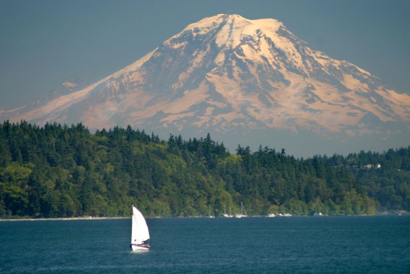Mount Rainier towers over a small sailboat plying the waters of Puget Sound near Port Orchard in this 2006 photo. A team of surveyors will hike to the summit this month to remeasure the Northwest’s tallest mountain.  (Associated Press)
