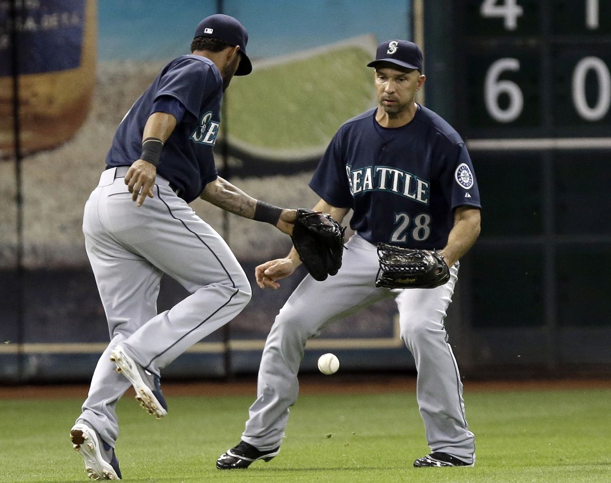M’s shortstop Robert Andino, left, is charged with an error after the ball drops between him and left fielder Raul Ibanez. (Associated Press)