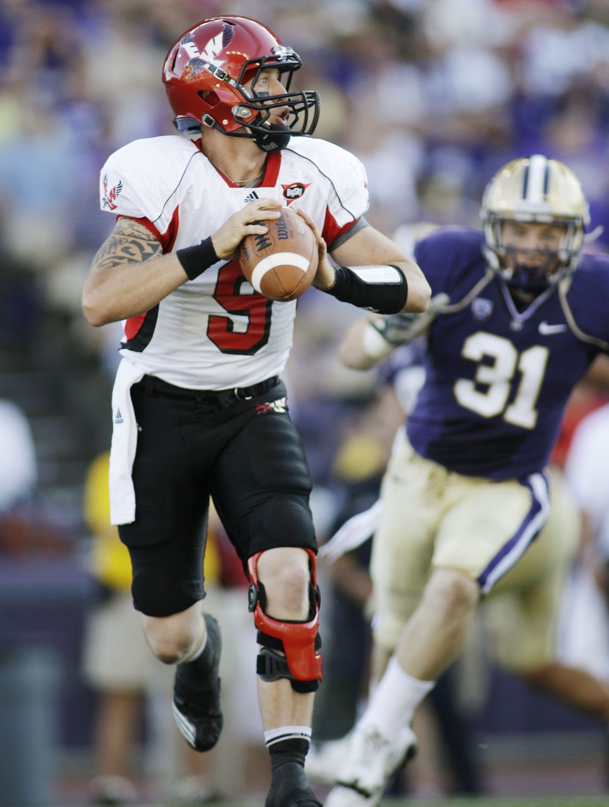 EWU quarterback Bo Levi Mitchell (9) looks to pass while evading UW’s Cort Dennison on Saturday. (Associated Press)
