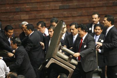 
Lawmakers scuffle, and one uses a chair to try to block an access at Mexico's National Congress, as opposition lawmakers try to block the arrival of President-elect Felipe Calderon on Friday. 
 (Photos by Associated Press / The Spokesman-Review)