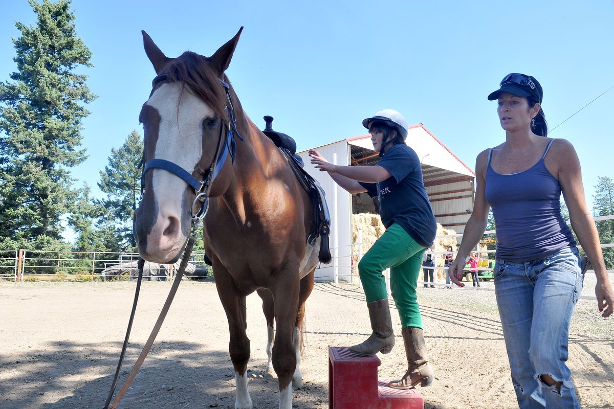 Volunteer Darla Green, right, walks around a horse named Spats while Tyler Bailey, 13, prepares to climb aboard for some saddle time at 2BU Youth Ranch Friday. (JESSE TINSLEY PHOTOS)