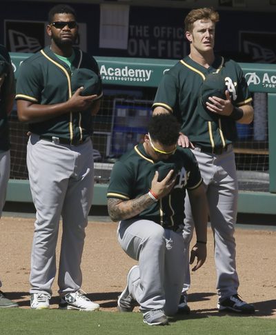 In this Sunday, Oct. 1, 2017 file photo, Oakland Athletics catcher Bruce Maxwell takes a knee during the national anthem next to teammates Mark Canha, right, and Raul Alcantara before a baseball game against the Texas Rangers in Arlington, Texas. Oakland Athletics catcher Bruce Maxwell says he will no longer kneel for the national anthem as he did last season as a rookie, when he became the first major leaguer to do so following the lead of many NFL players. He spoke Tuesday, Feb. 13, 2018 as the As pitchers and catchers reported to spring training. (LM Otero / Associated Press)