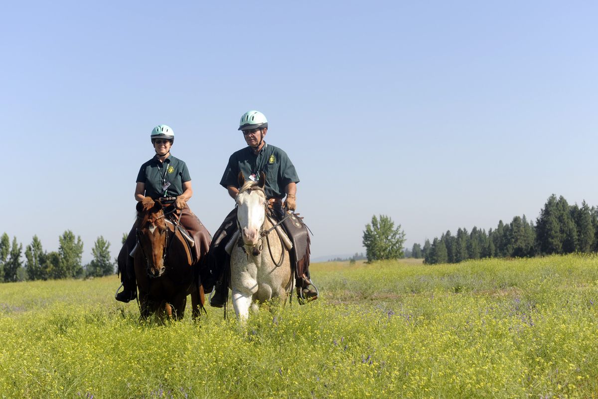 SCOPE volunteers Michelle LeVar, left, and Mike Bryarly ride   horses Junior and Pinky to patrol rural parts of Spokane County. (Jesse Tinsley / The Spokesman-Review)