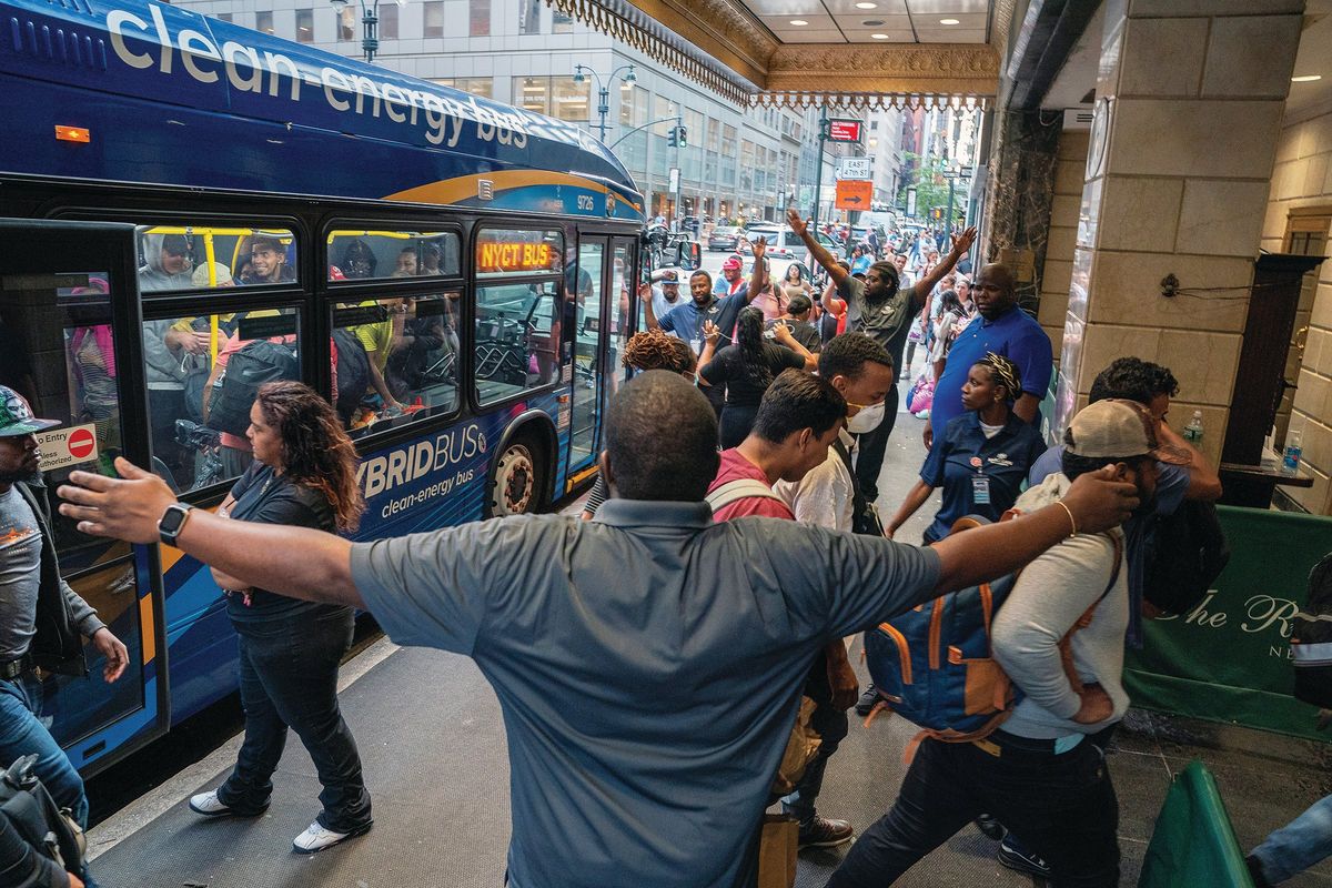 Above: Arriving migrants are ushered into a processing center in Manhattan, N.Y., on July 31. Migrant waves have put northern “sanctuary” cities, like New York, increasingly on edge, their budgets stretched, their communities strained. Left: Asylum seekers camp out in a Chicago police station on May 8. The strain of migrants in Chicago, New York, Los Angeles and other cities has taxed resources, divided Democrats and put pressure on President Joe Biden to act.  (DAVID DEE DELGADO)