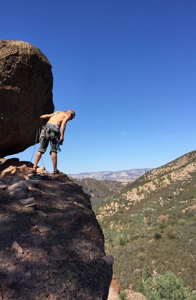 Kim Midstokke leans over the rappel chute on the Pinnacles Discovery wall to ensure his sister does not plummet to her death while descending.