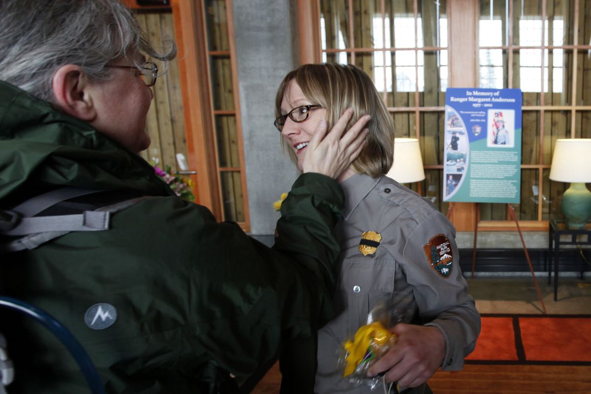Mount Rainier National Park Ranger Rebecca Roland, right, is greeted by volunteer Ranger Rose Evans in front of a memorial for Ranger Margaret Anderson in the visitors center at the Paradise area of the park Saturday. (Associated Press)