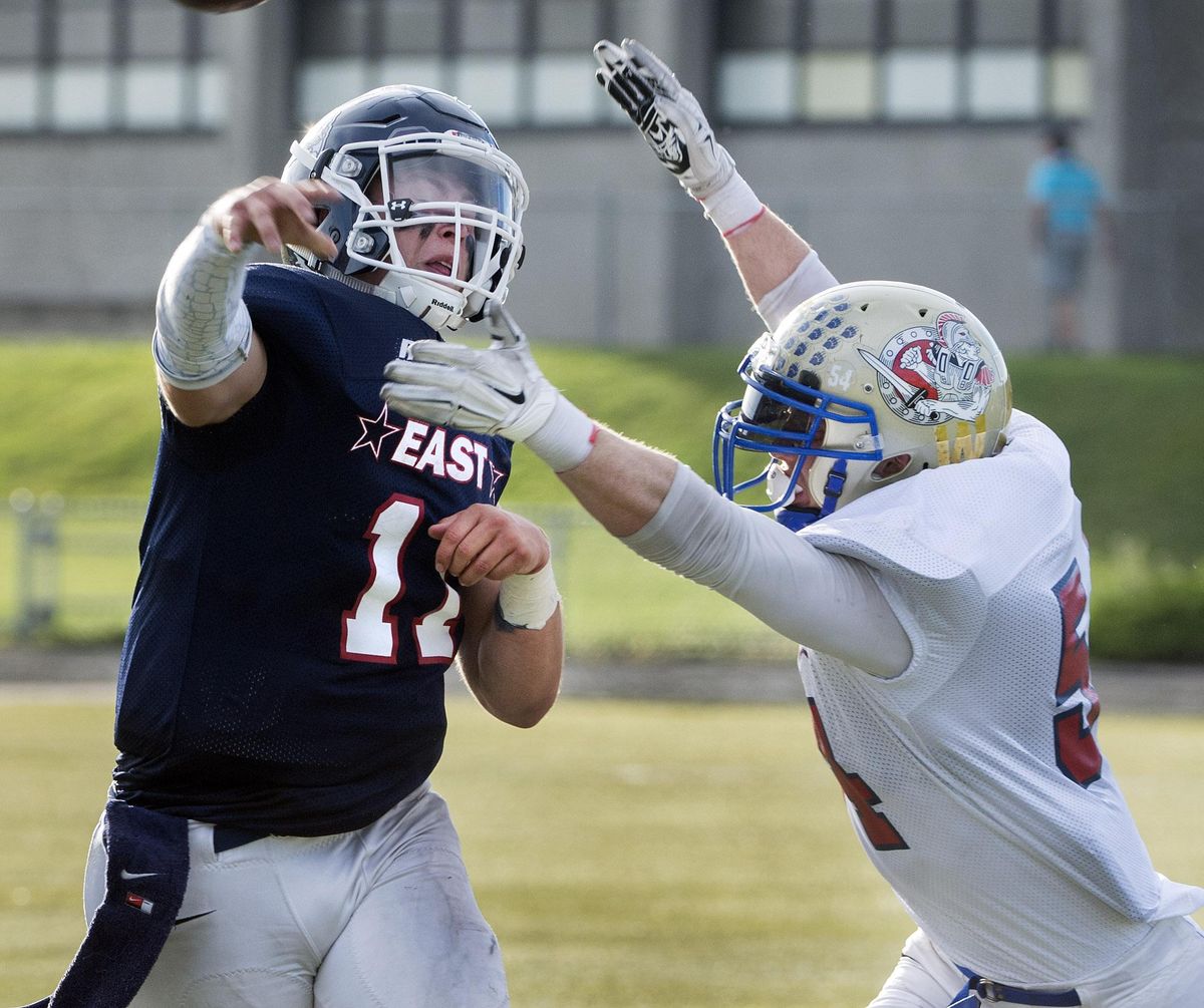 East QB Liam Bell, of Gonzaga Prep, gets pressure from West