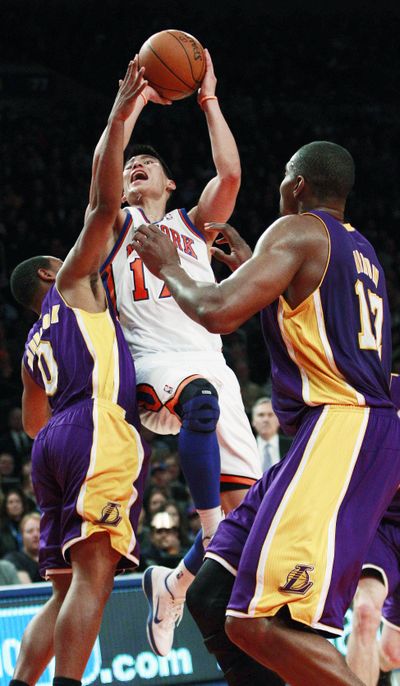 New York’s Jeremy Lin drives between Los Angeles’ Andrew Goudelock, left, and Andrew Bynum during the first half. (Associated Press)