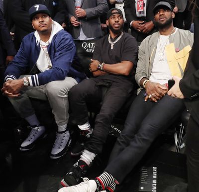 Carmelo Anthony, Chris Paul and LeBron James, from left, watch during the first half of an NBA basketball game between the Brooklyn Nets and the Miami Heat, Wednesday, April 10, 2019, in New York. The three were watching Miami Heat guard Dwyane Wade play the final NBA game of his career. (Kathy Willens / Associated Press)