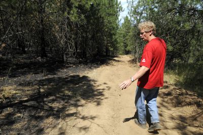 Glen MacPhee  walks Thursday down the line between burned and unburned terrain. He dug a fire line to stop last week’s wildfire from burning more of his property.  (Jesse Tinsley / The Spokesman-Review)
