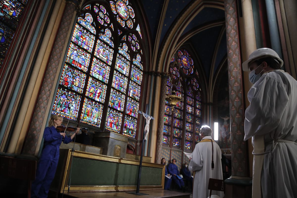 Notre Dame rector Patrick Chauvet, second right, stands as part of the Maundy Thursday ceremony, while cellist Marina Chiche, left, performs in Notre Dame Cathedral, Thursday, April 1, 2021, almost two years after a massive fire ravaged the Gothic cathedral.  (Christophe Ena)