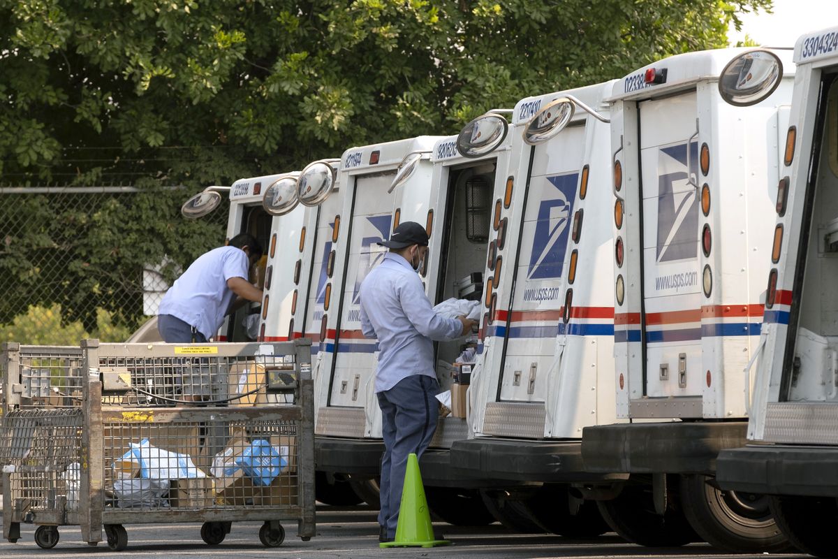 FILE - In this Aug. 20, 2020 file photo, postal workers load their mail delivery vehicles at the Panorama city post office in Los Angeles. The Nov. 3 election will test California