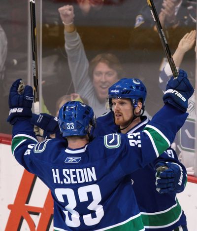 Vancouver Canucks’ Daniel Sedin, right, celebrates one of his two goals against the Blackhawks with his twin brother, Henrik. (Associated Press)