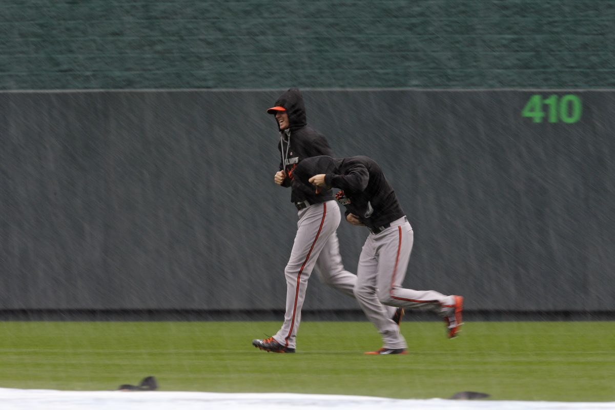 Orioles players are chased back to dry ground as rain forces postponement of Game 3 of ALCS in Kansas City. (Associated Press)