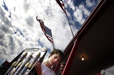 
Steven Obrycki, 12, carries fireworks to his family's car at the Discount Fireworks stand run by the Lions Club in Airway Heights on Saturday. His mother, Marlisa, said the family easily spent $300. 