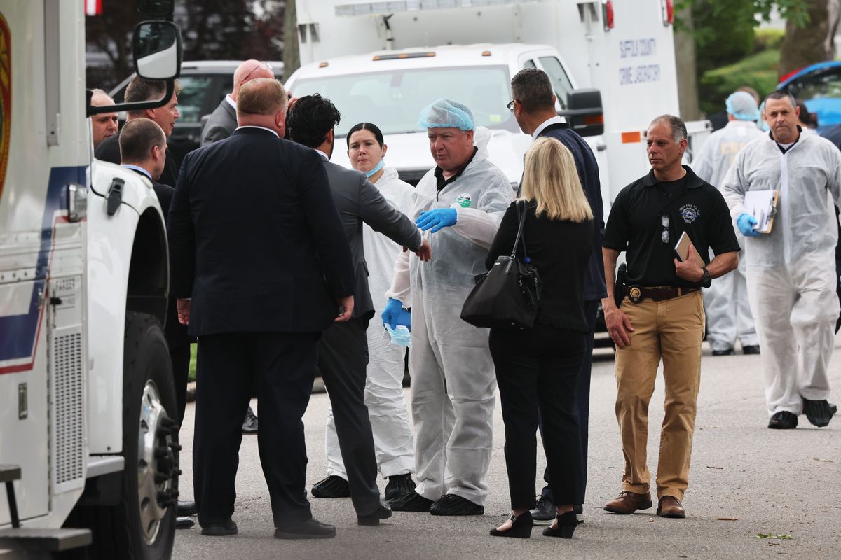 Law enforcement officials are seen as they investigate the home of a suspect arrested in the unsolved Gilgo Beach killings on Friday in Massapequa Park, N.Y.  (Michael M. Santiago)