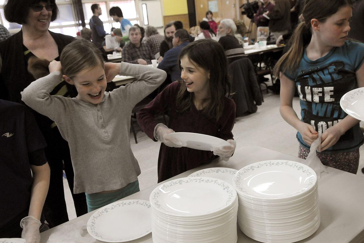 Sisters Brianna 9, and Maggie Crane, 8, stand in line to pick up Christmas dinner plates to serve to guests at St. Charles Catholic Church during the annual Christmas dinner, Friday, Dec. 25, 2015, in Spokane, Wash. This is the first time the Crane family has volunteered for the church