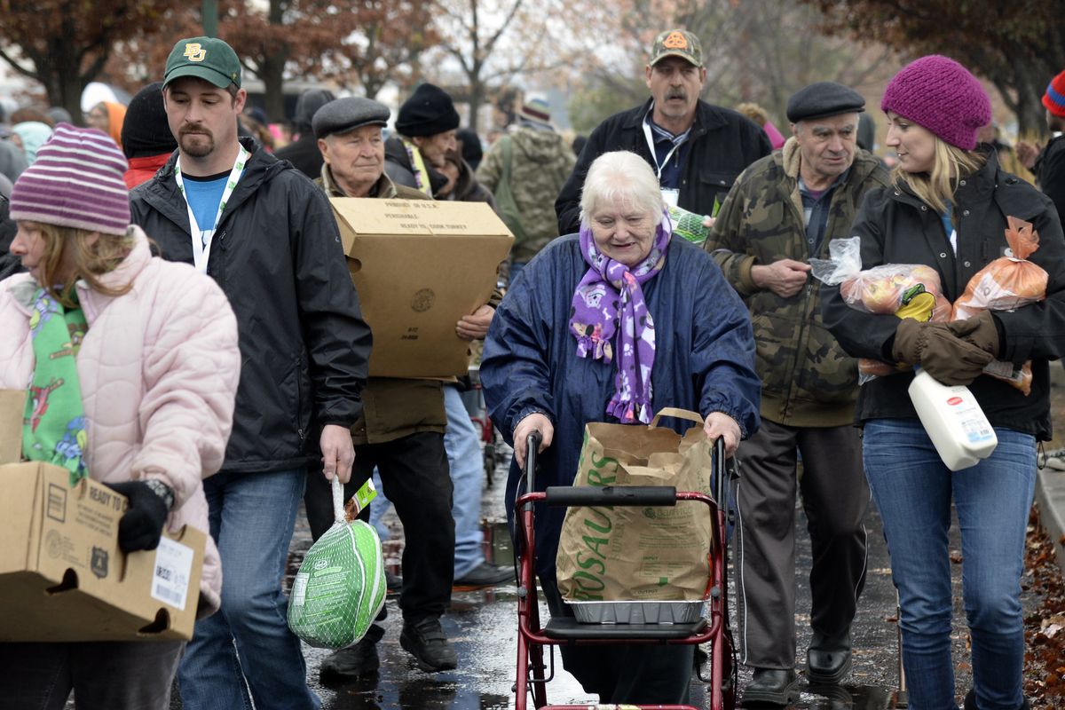 Thankful recipients: Claudia Van Vliet, center, gets help from volunteer Jill Ham, right, and Marty Grieser, second from left, in carrying a turkey and other food items to Van Vliet’s ride after visiting the annual turkey giveaway at the Spokane Arena on Tuesday. The operation to raise money for 11,000 Thanksgiving dinners was mounted by KREM2 weatherman Tom Sherry, the Salvation Army, Second Harvest food bank and many donors. (PHotos by Jesse Tinsley)