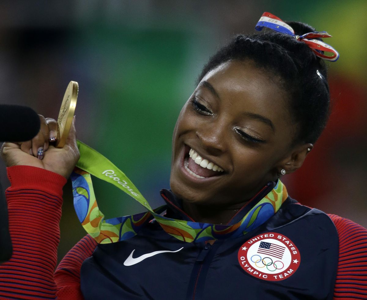 Simone Biles displays her gold medal after winning the floor exercise. Biles, who won five medals, is to carry the American flag in the Sunday’s closing ceremony. (Rebecca Blackwell / Associated Press)